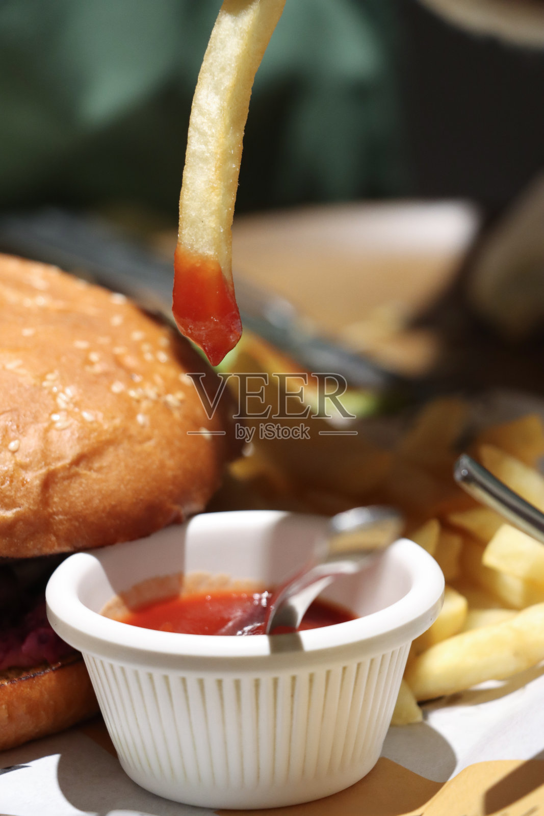 近景是酥脆金黄的薯条蘸着番茄酱，芝士汉堡夹着芝麻汉堡，一堆炸土豆片，聚焦在前景照片摄影图片