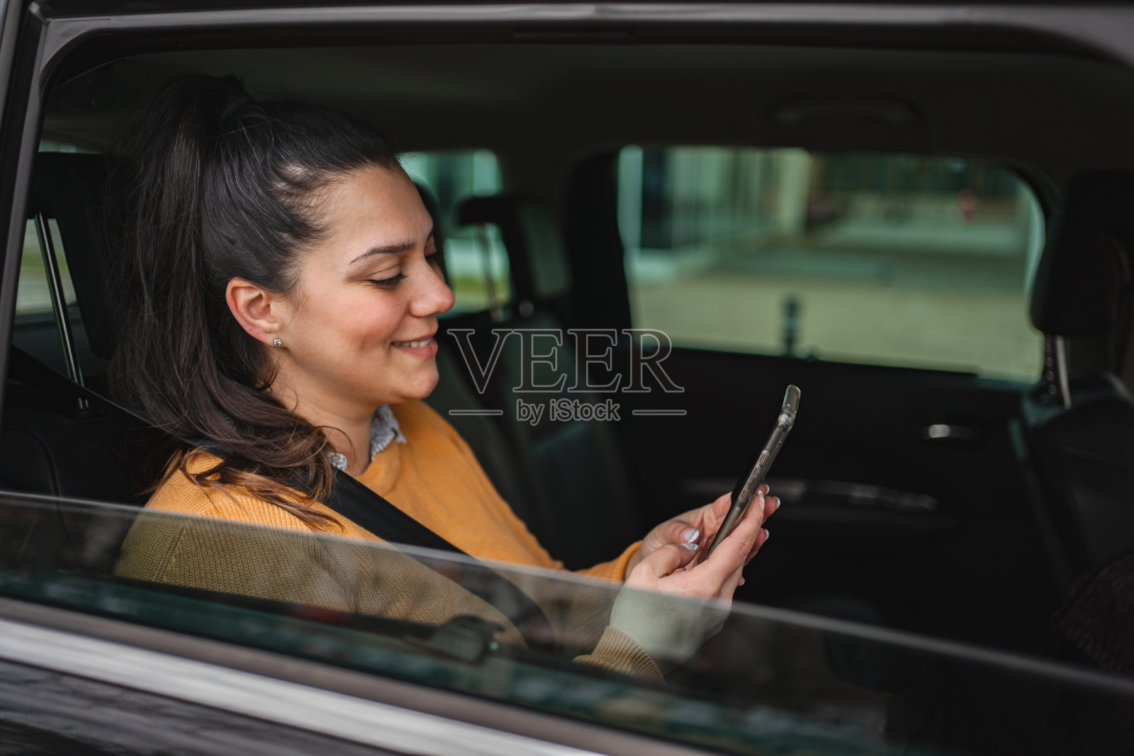 一名女子在汽车后座上玩手机照片摄影图片