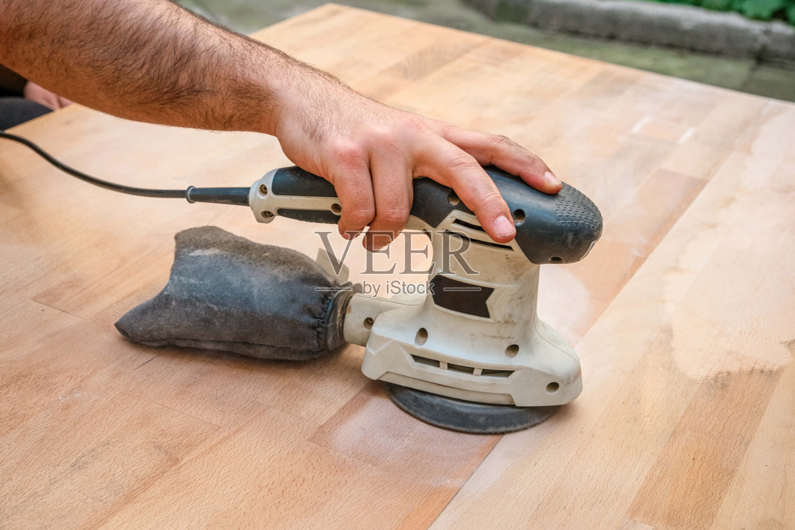 一个人在车间里使用轨道磨砂机。木匠手的特写照片摄影图片
