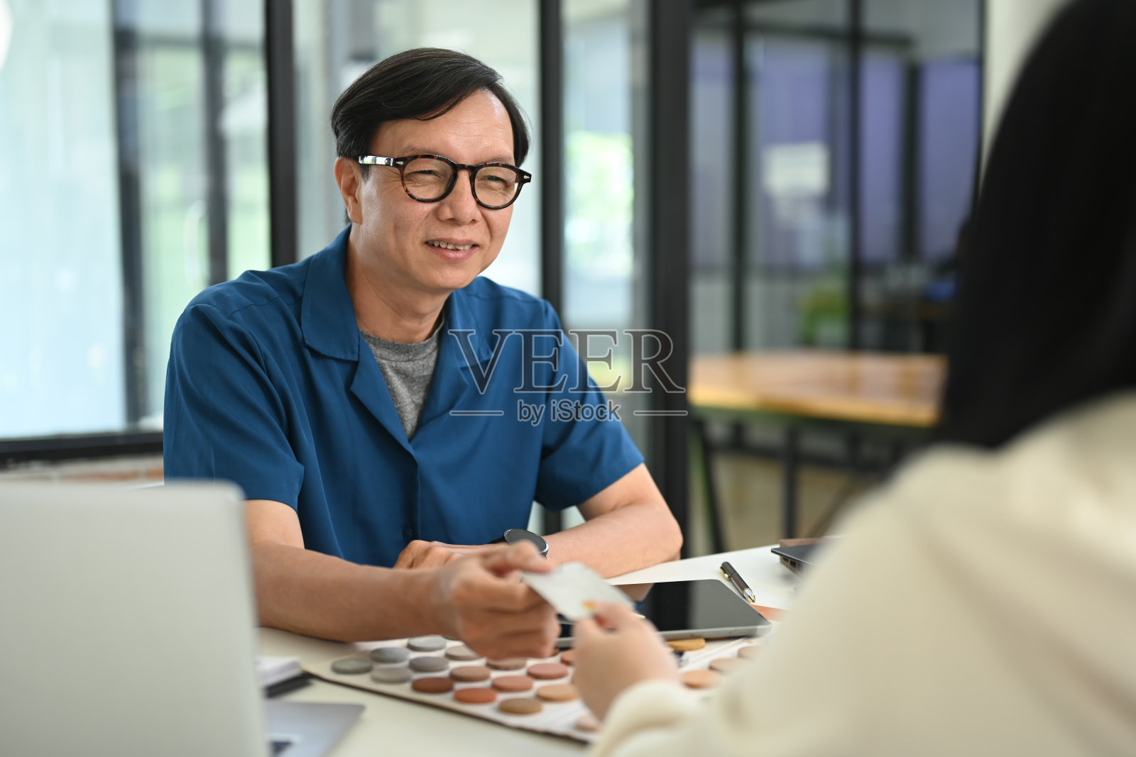 友好的资深男室内设计师在签约后收到女客户的信用卡照片摄影图片