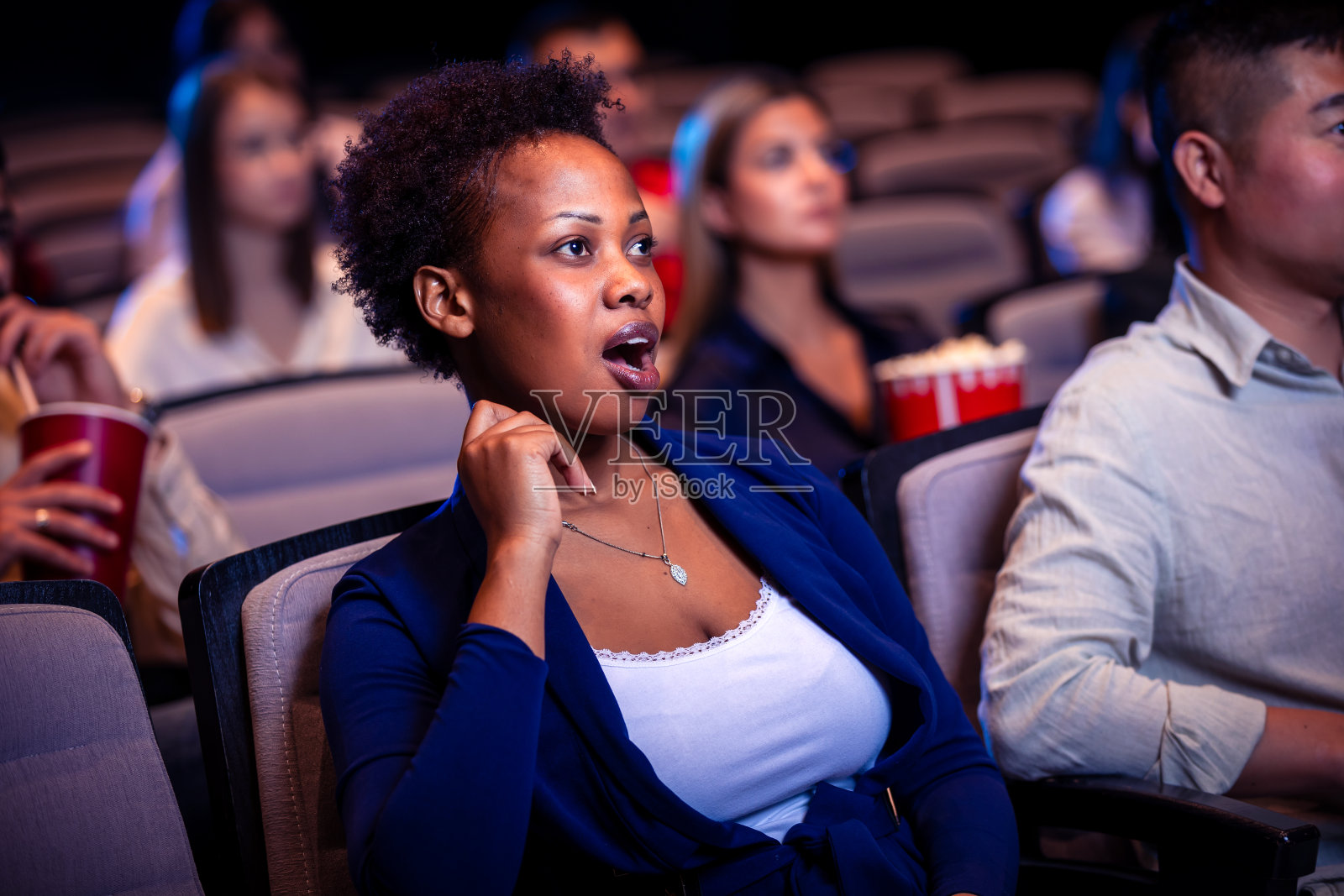在电影院看电影的非裔美国妇女震惊不已。照片摄影图片