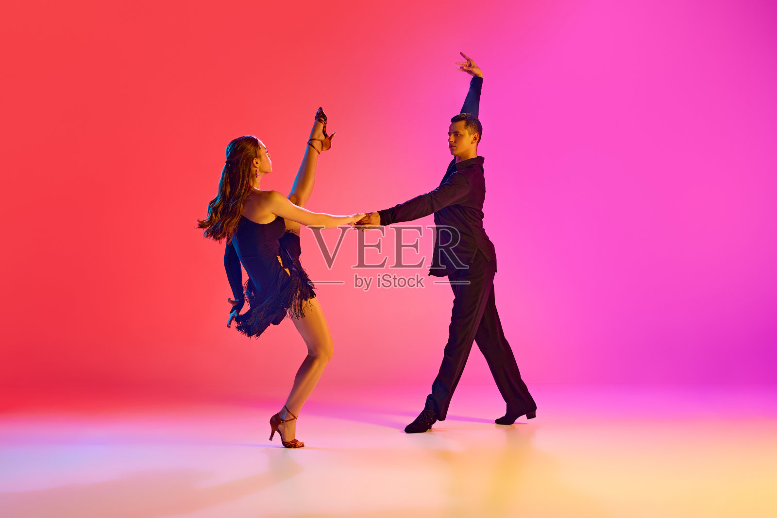 专业舞厅舞者在黑色舞台服装表演霓虹灯对充满活力的渐变背景。照片摄影图片