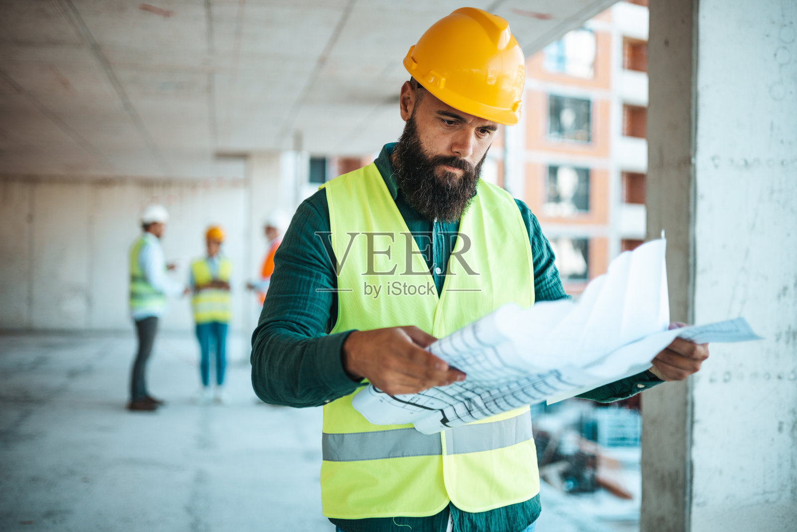 专注的男建筑工人在现场审查计划照片摄影图片