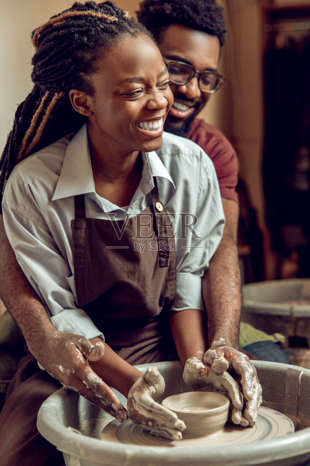 一对快乐的夫妇一起在陶器轮上工作，看起来很享受照片摄影图片