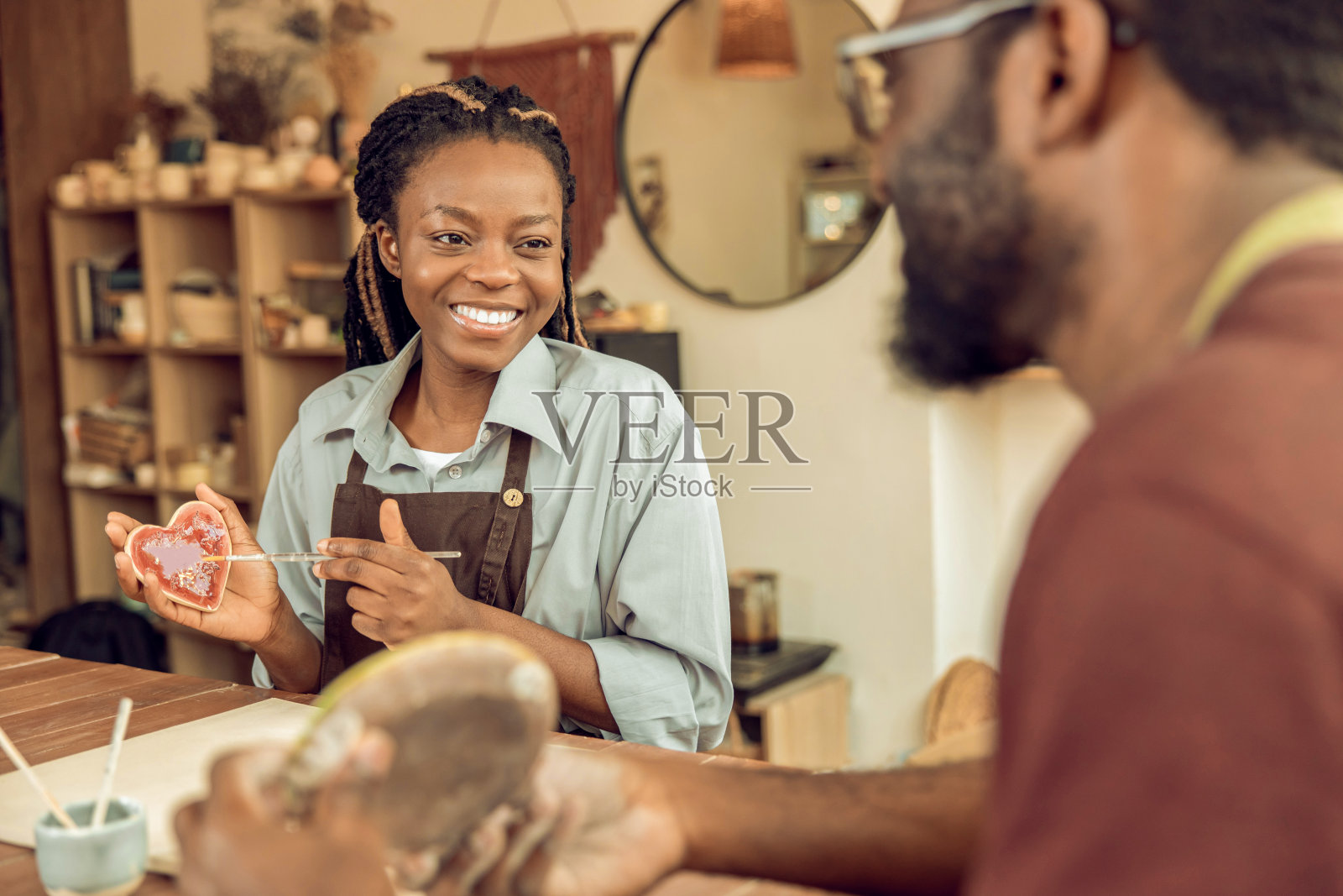 两个人坐在桌子旁摆弄陶器照片摄影图片