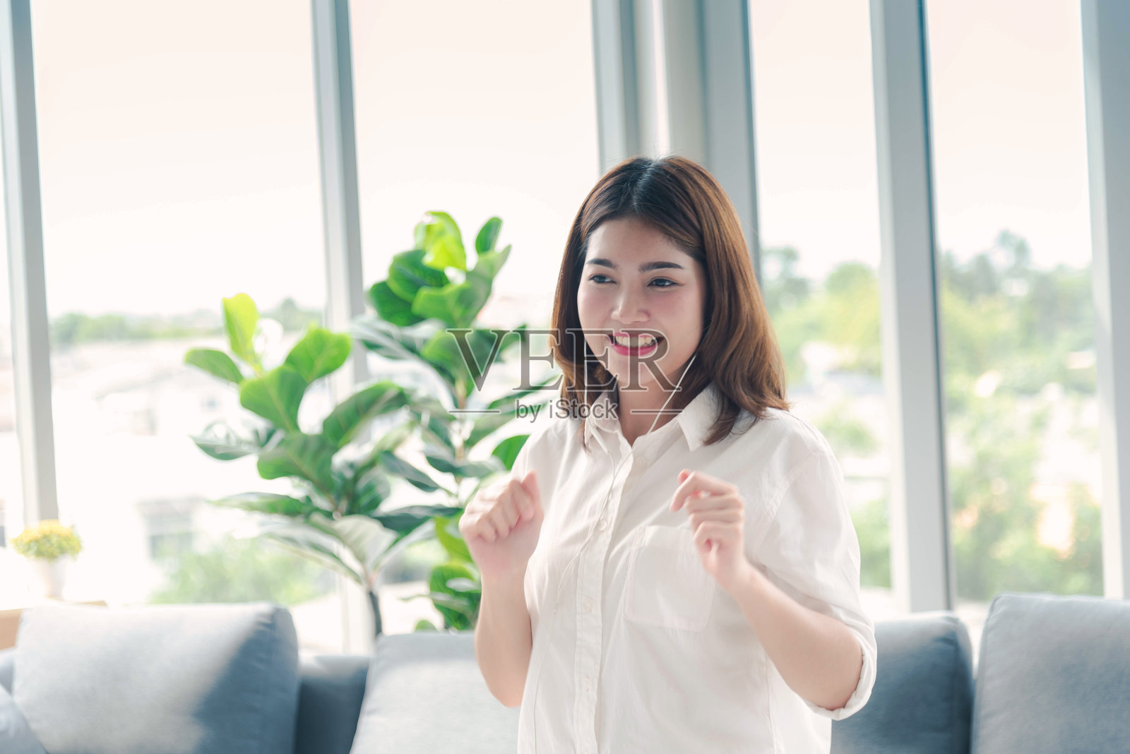 快乐的亚洲舞蹈女人用耳机听音乐从智能手机快乐舞蹈在家里的客厅。音乐心理治疗师放松女人。快乐健康女性舞蹈锻炼健康照片摄影图片