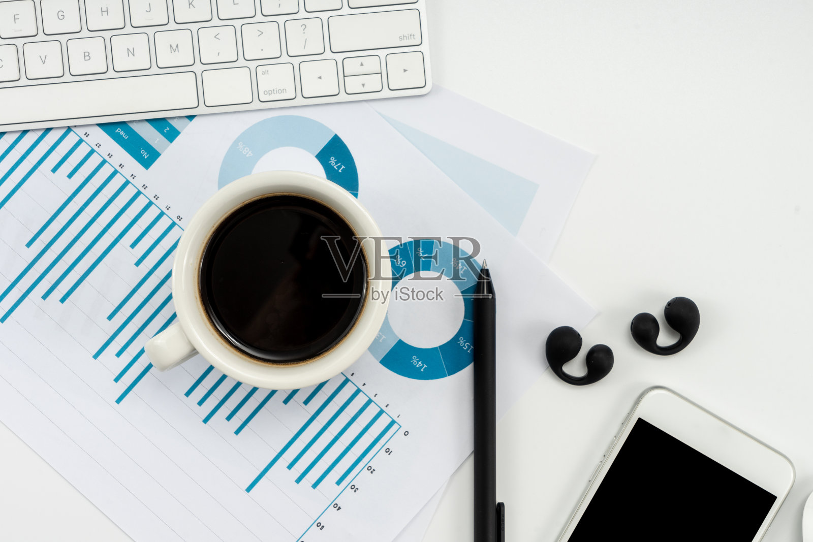 办公场所配备智能手机、一杯咖啡、财务图表等工作工具。照片摄影图片