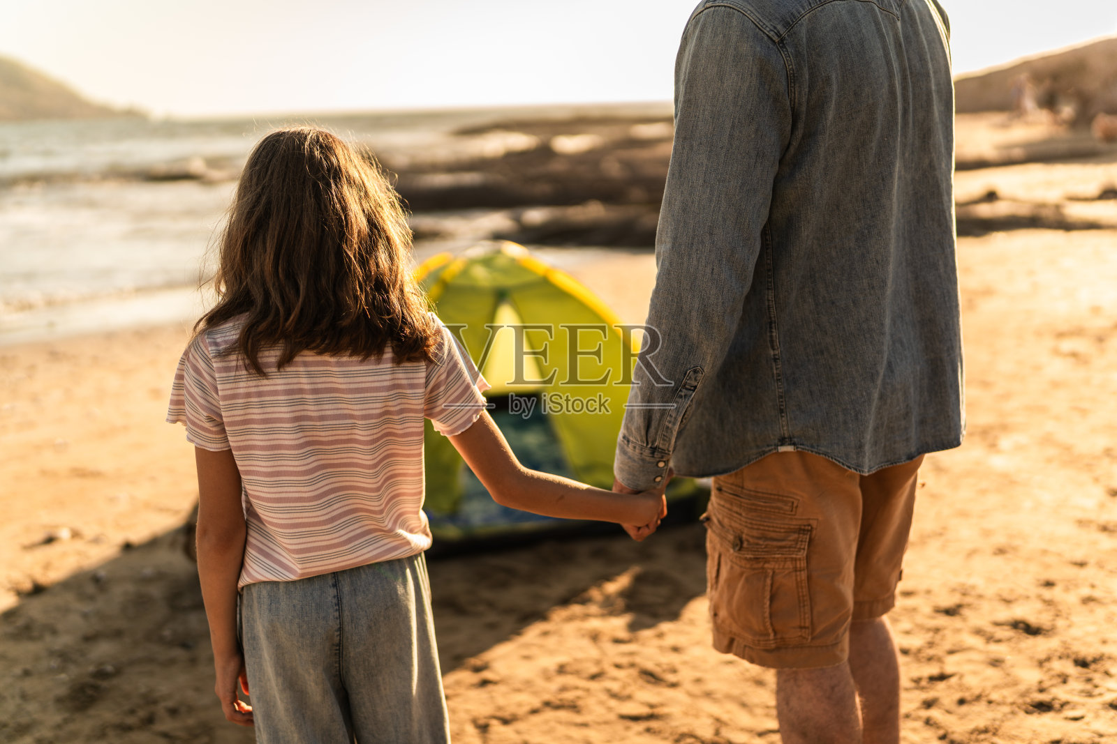 父亲和女儿在沙滩上牵手的特写照片摄影图片