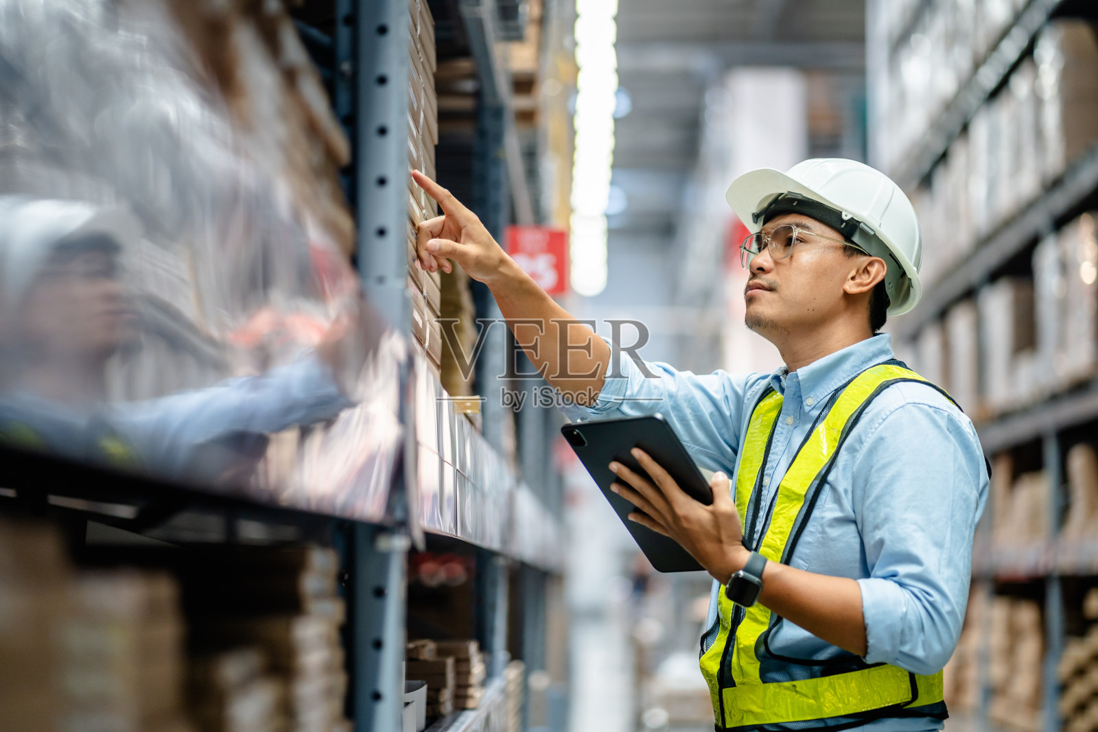 商人或经理使用数字平板电脑查看大型仓库货架上的库存，智能仓库管理系统，供应链和物流网络技术概念。照片摄影图片