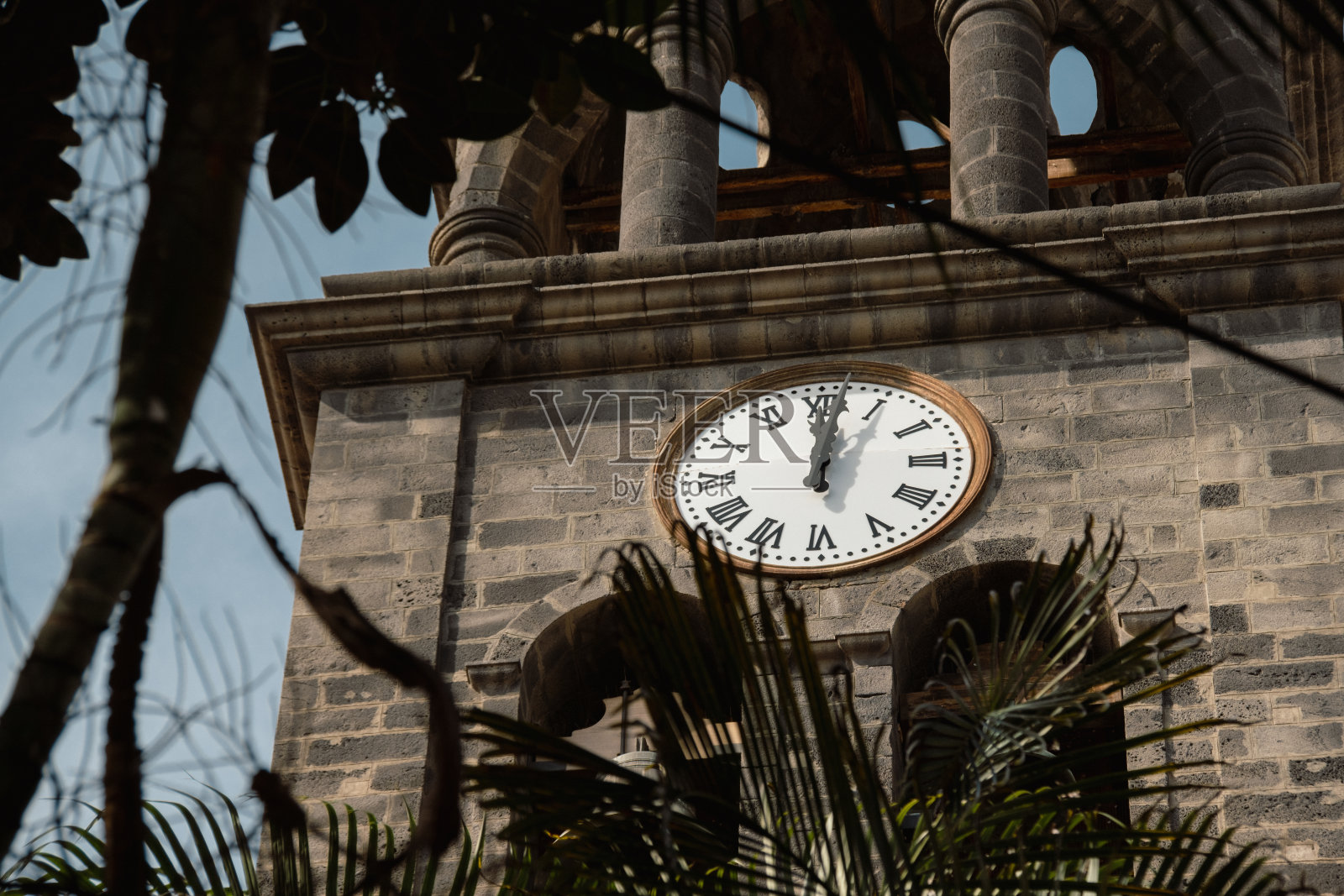 在热带欧洲国家的主要旧砖建筑或天主教堂的钟楼上，带有复古指针的时钟照片摄影图片