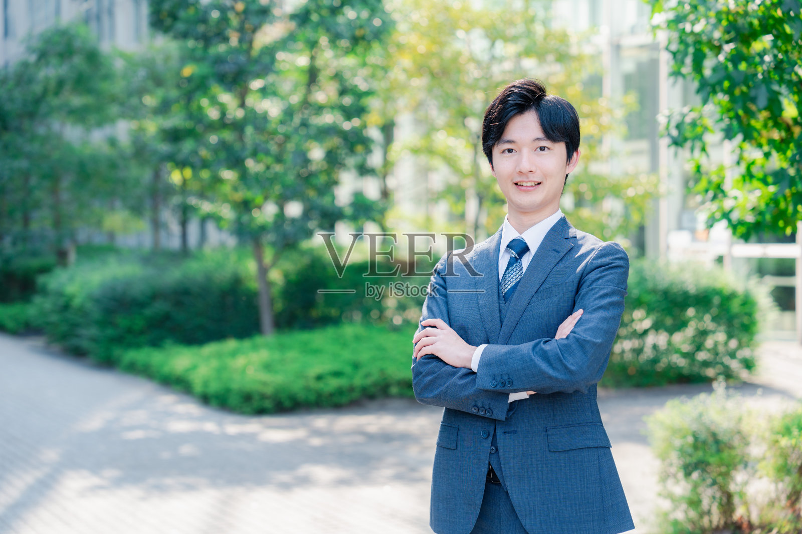 穿着西装，双臂交叉的年轻商人。照片摄影图片