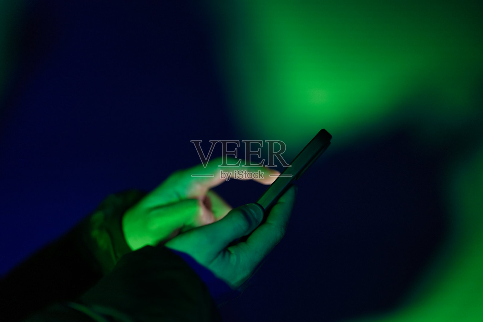 手指触摸智能手机屏幕与绿色和蓝色的光照片摄影图片