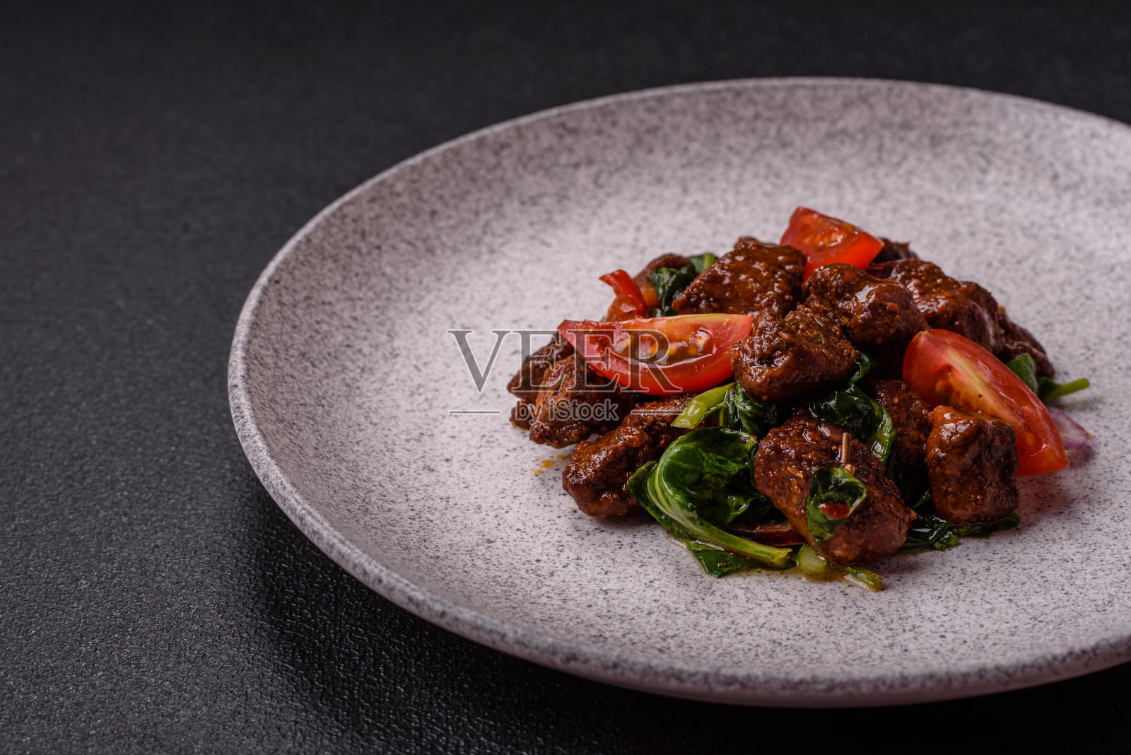 美味的热沙拉，有肉、菠菜、西红柿、盐、香料和香草照片摄影图片