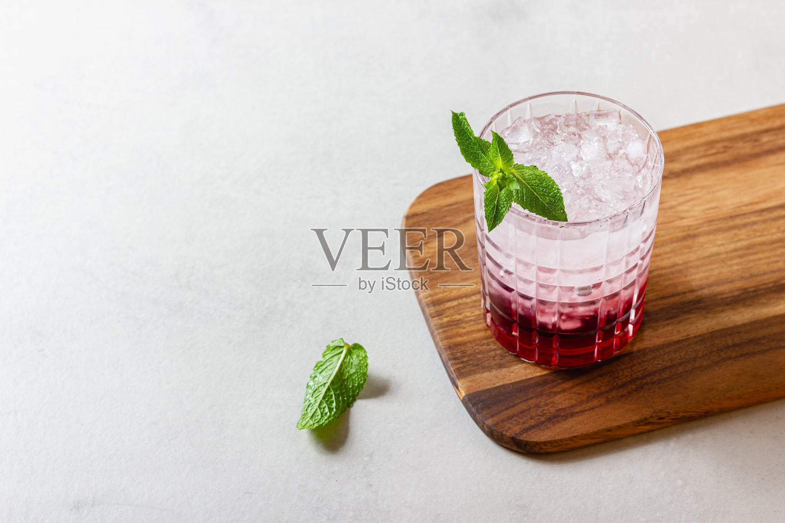 一杯加冰的鸡尾酒，放在木砧板上照片摄影图片