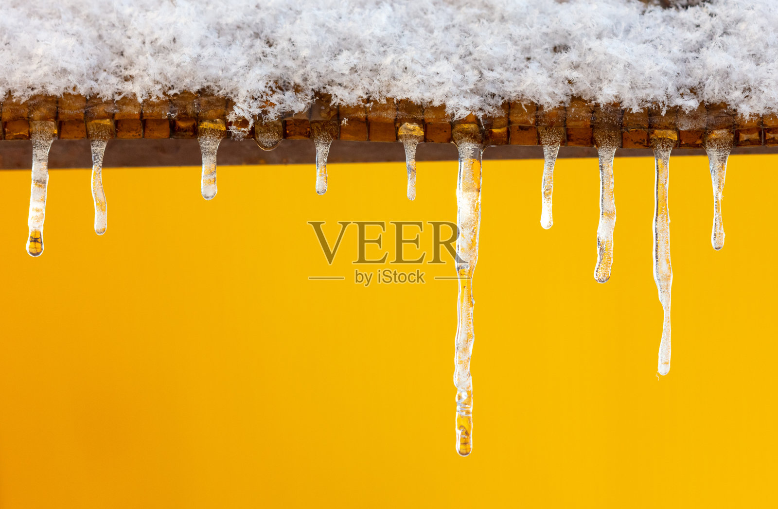 黄色背景上的冰柱照片摄影图片