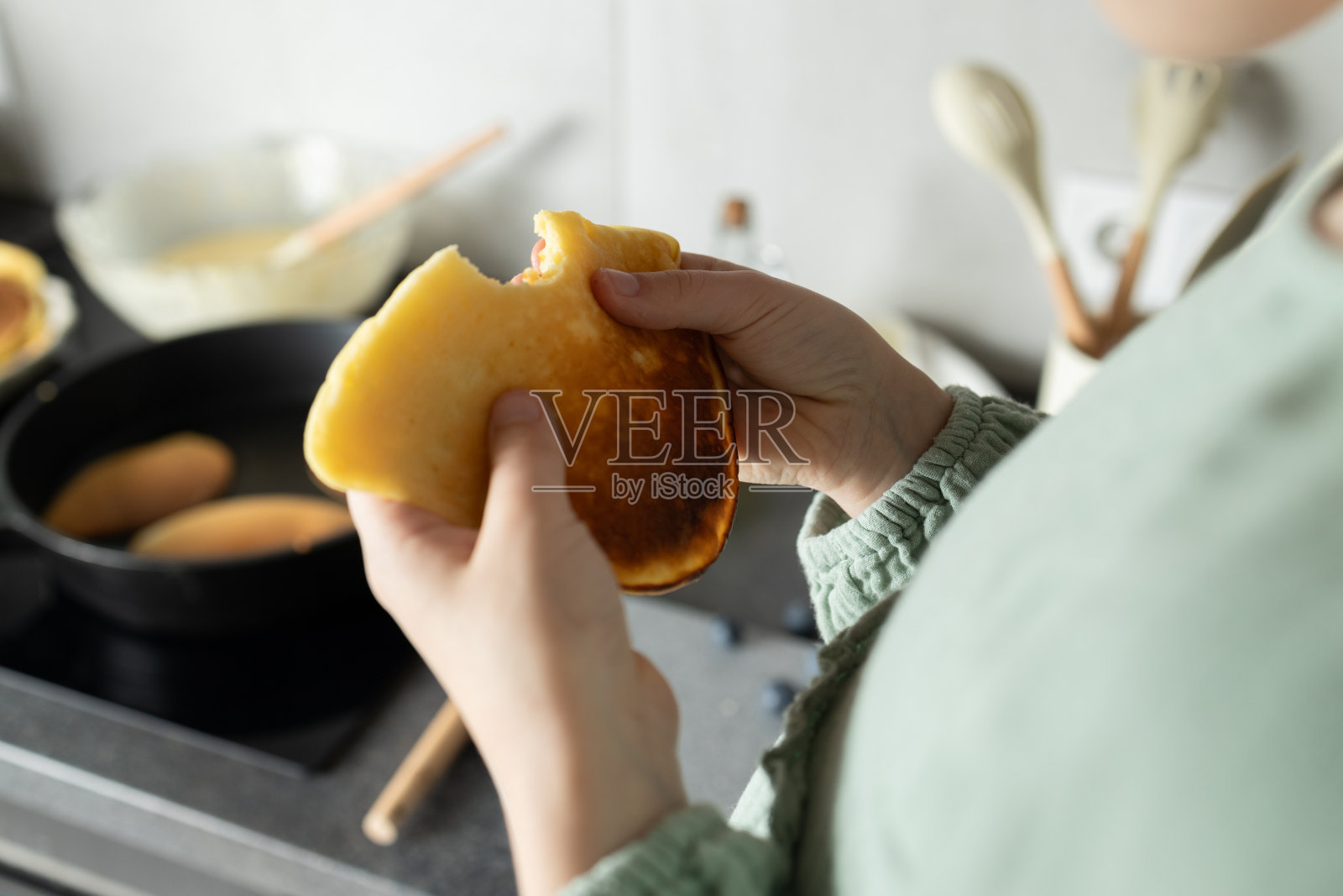 孩子的手拿着被咬过的煎饼在家里的火炉旁照片摄影图片