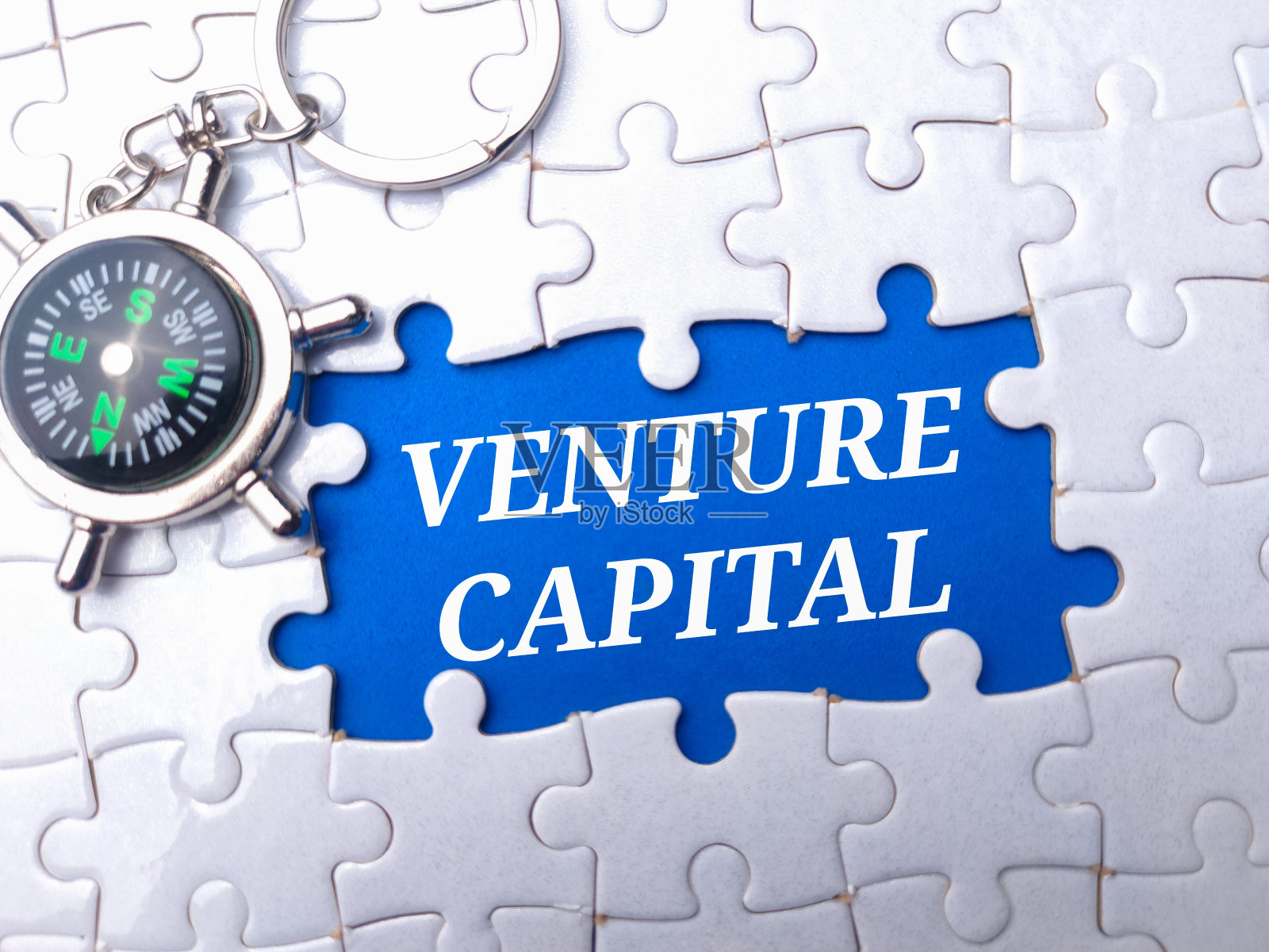 指南针和白色拼图，上面写着“风险投资”照片摄影图片