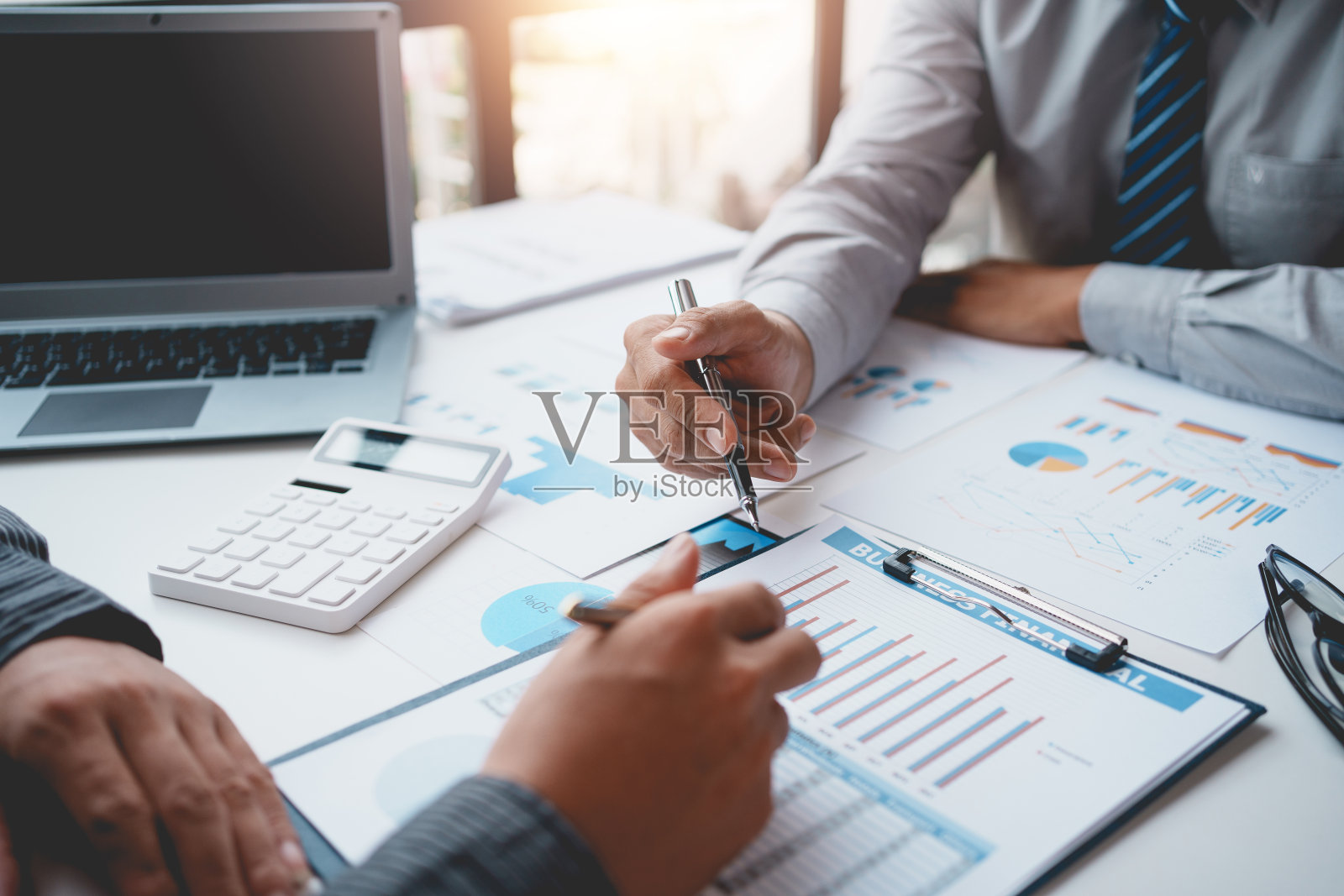 两个商人在会议上一起计划投资。商业顾问指图表特写，分析财务报告和利润赤字。照片摄影图片