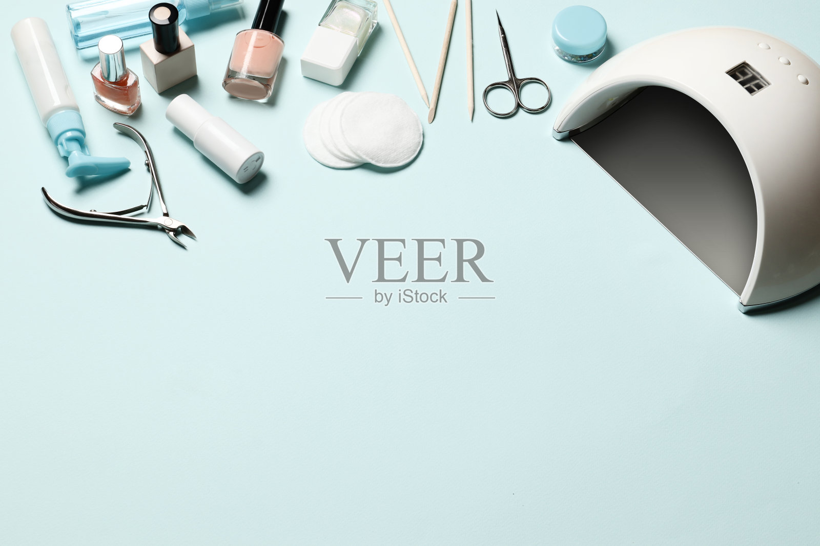 美甲工具和化妆品的组成，指甲油，美甲灯，蓝色背景的紫外线灯。放文字的地方。照片摄影图片