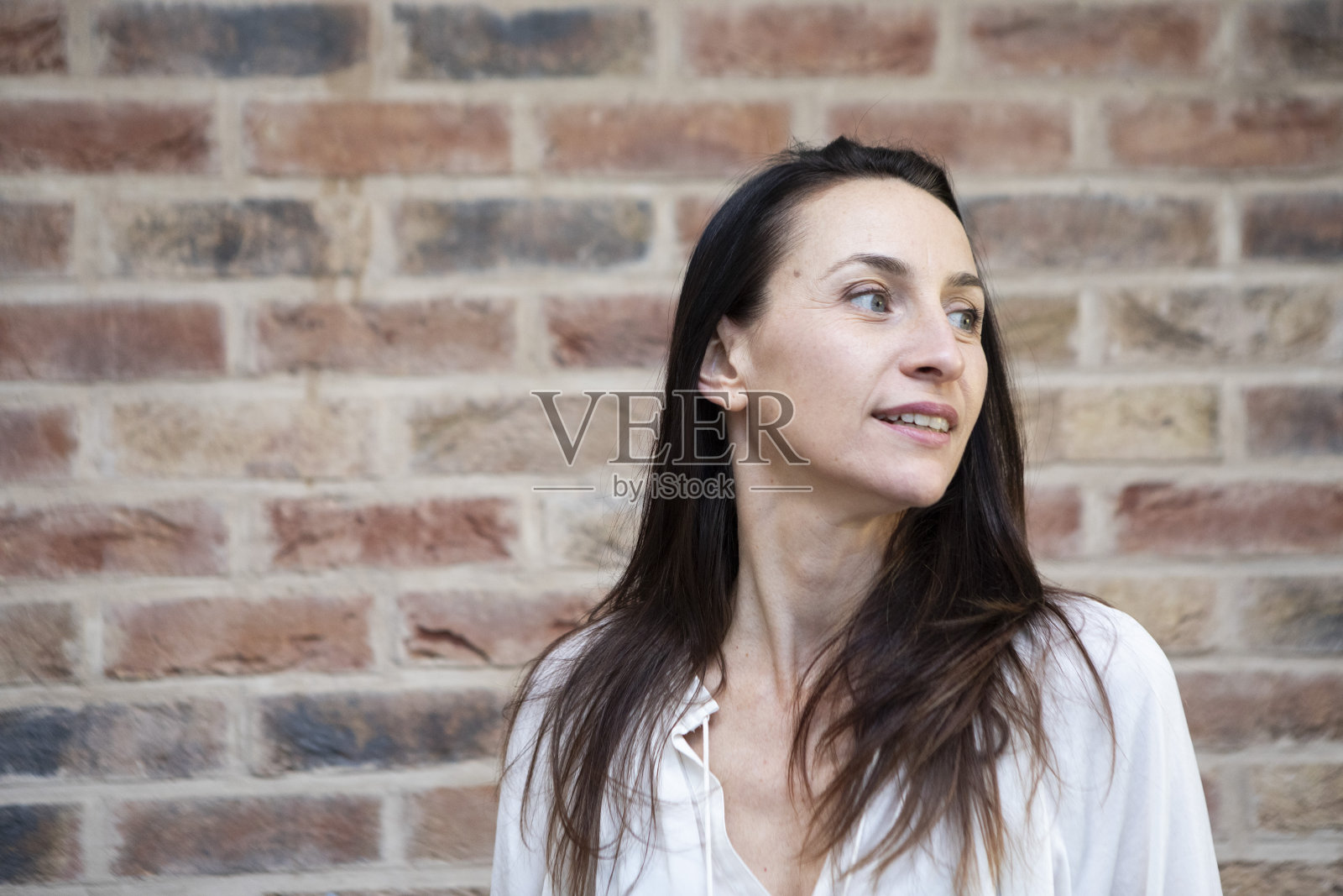 站在砖墙旁的快乐女人照片摄影图片