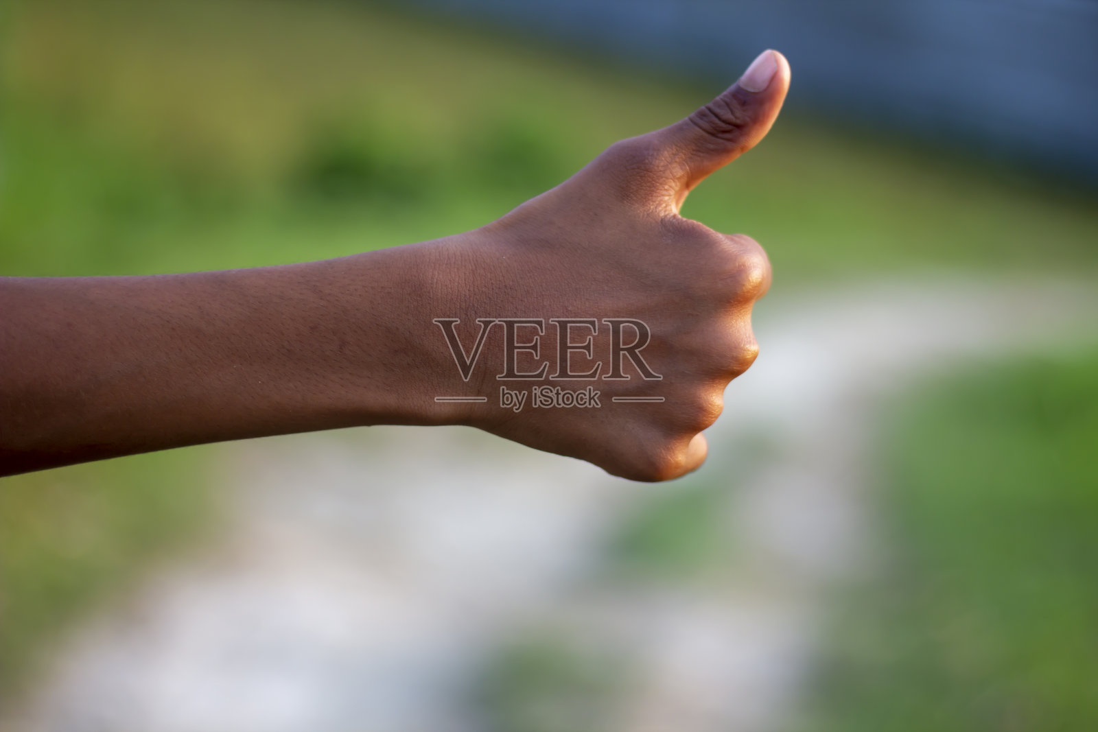 一个男人的拇指朝上，背景模糊照片摄影图片