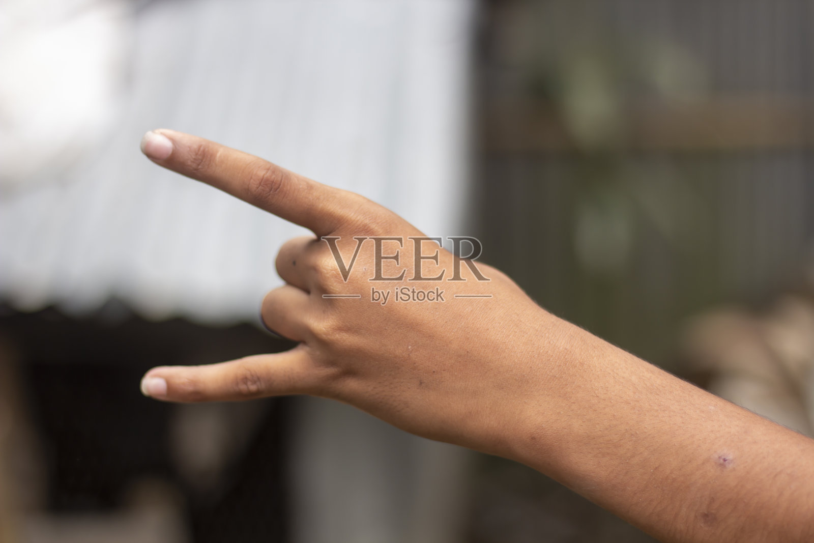 一个男人用两只手指指着前方，模糊了背景照片摄影图片