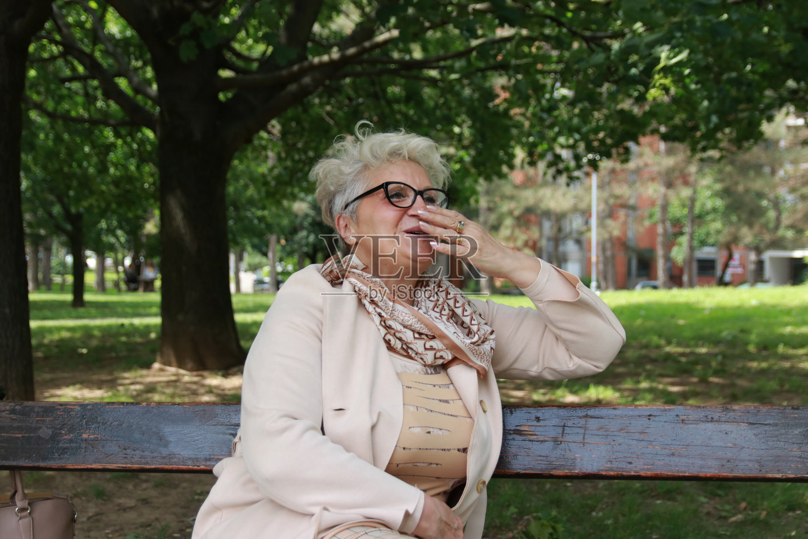 快乐的大四女生坐在公园的长椅上照片摄影图片