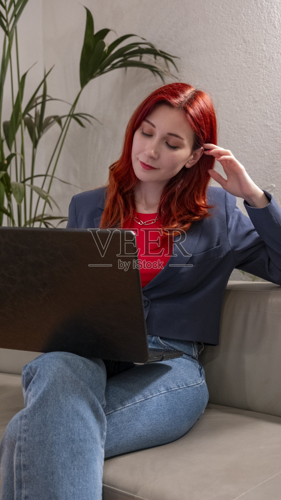 一位美丽迷人的红发女商人在办公室外用笔记本电脑工作。照片摄影图片