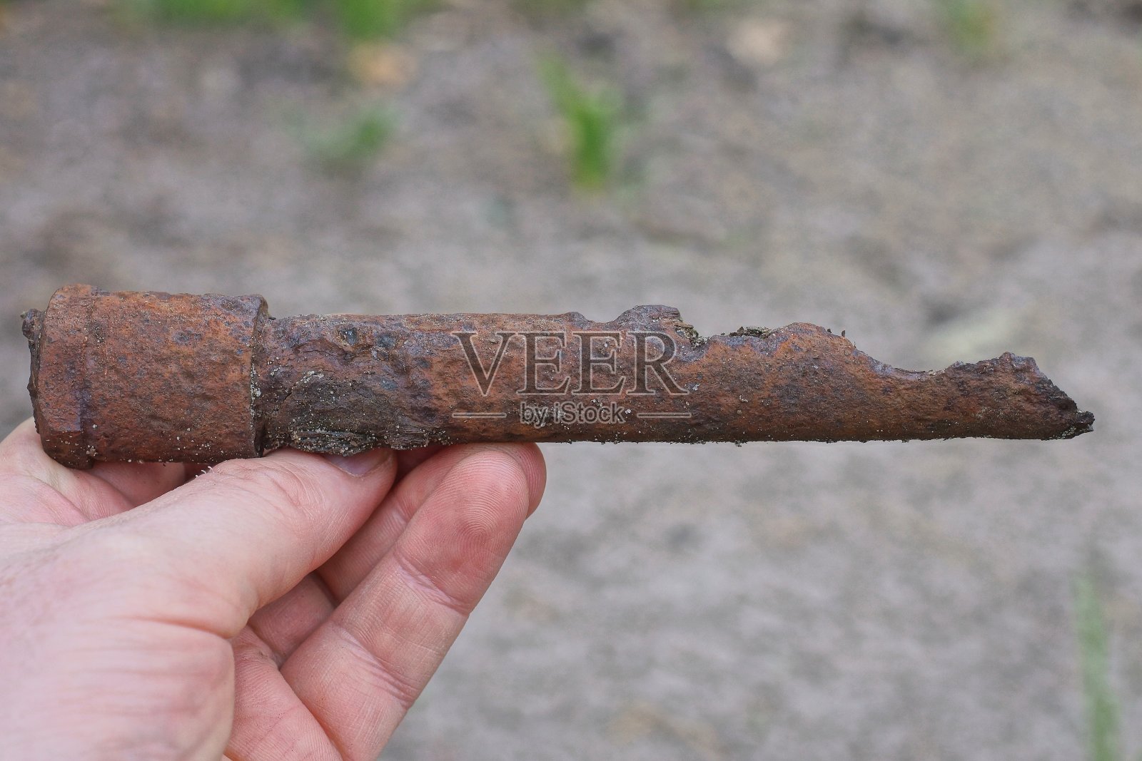 手里拿着一根生锈的旧铁棒照片摄影图片