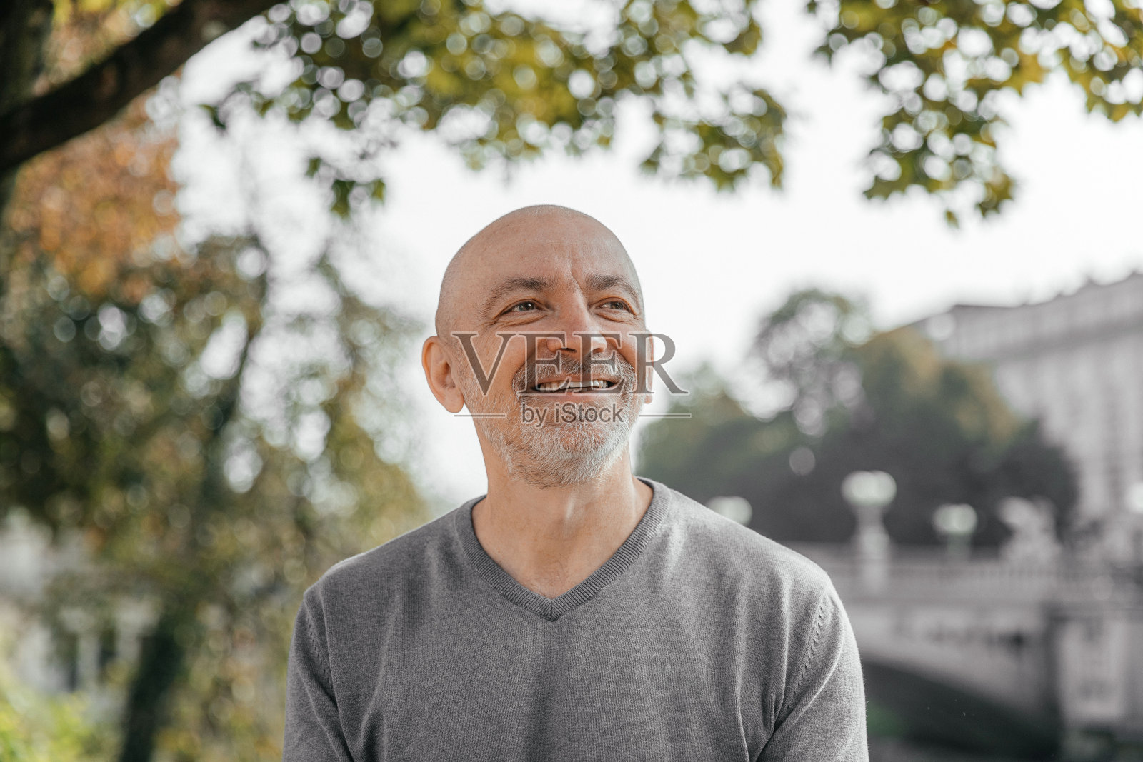 穿着灰色毛衣的快乐老人坐在公园里，热情地微笑着照片摄影图片