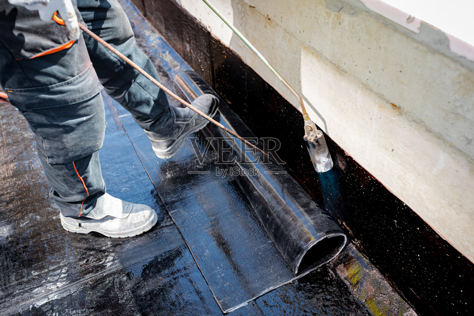 工人使用燃气燃烧器，丙烷喷灯熔化和排列树脂与沥青展开箔照片摄影图片