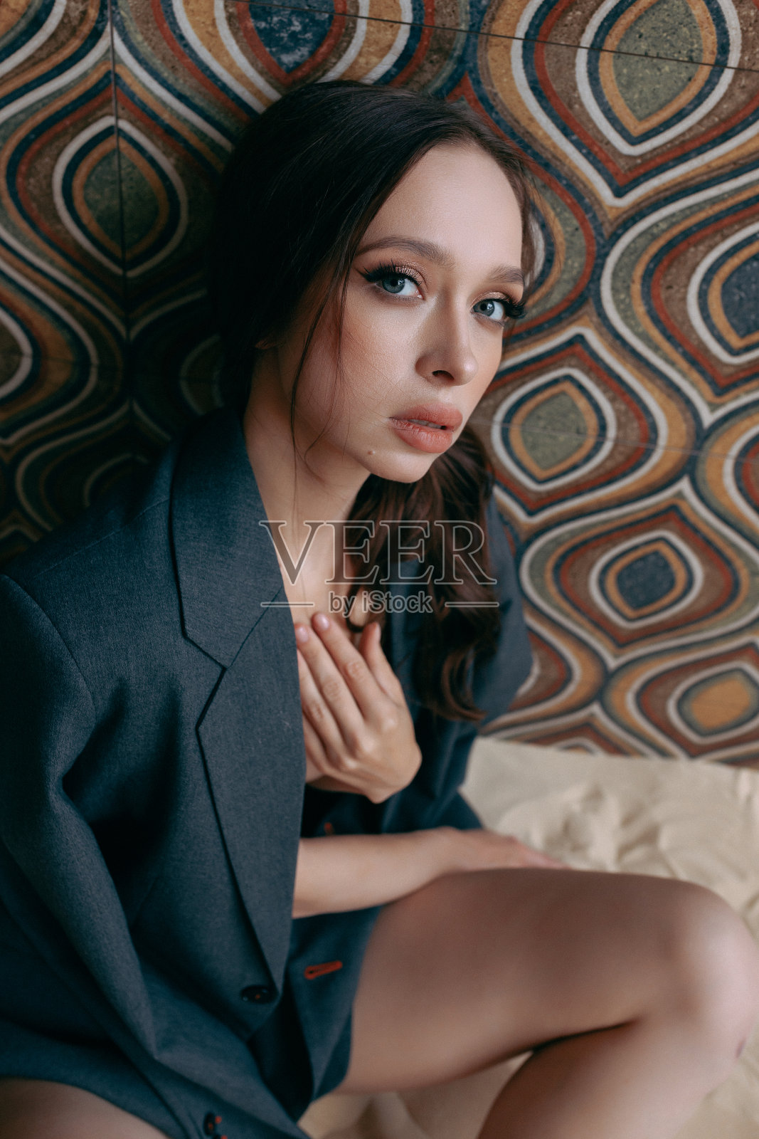 一个穿着未扣的夹克和牛仔裤的女人靠墙摆姿势照片摄影图片