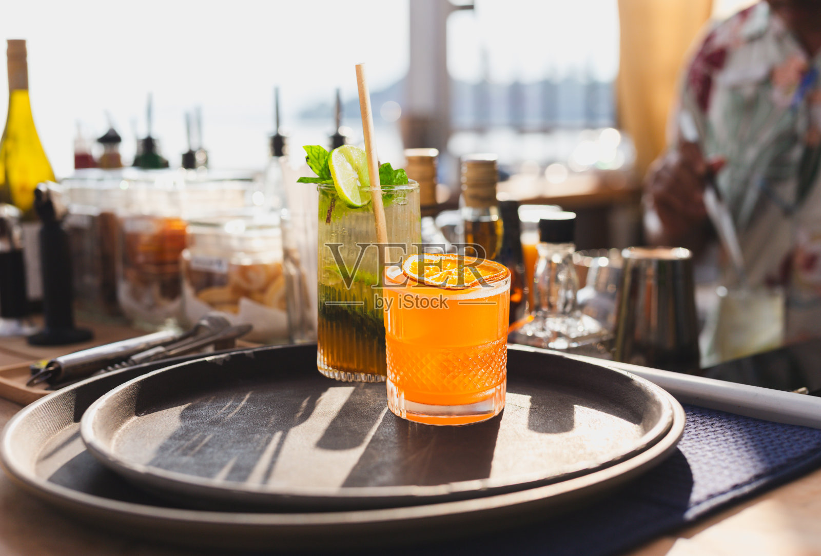 鸡尾酒装在玻璃杯里，用吸管在柜台上方的吧台上饮用。照片摄影图片