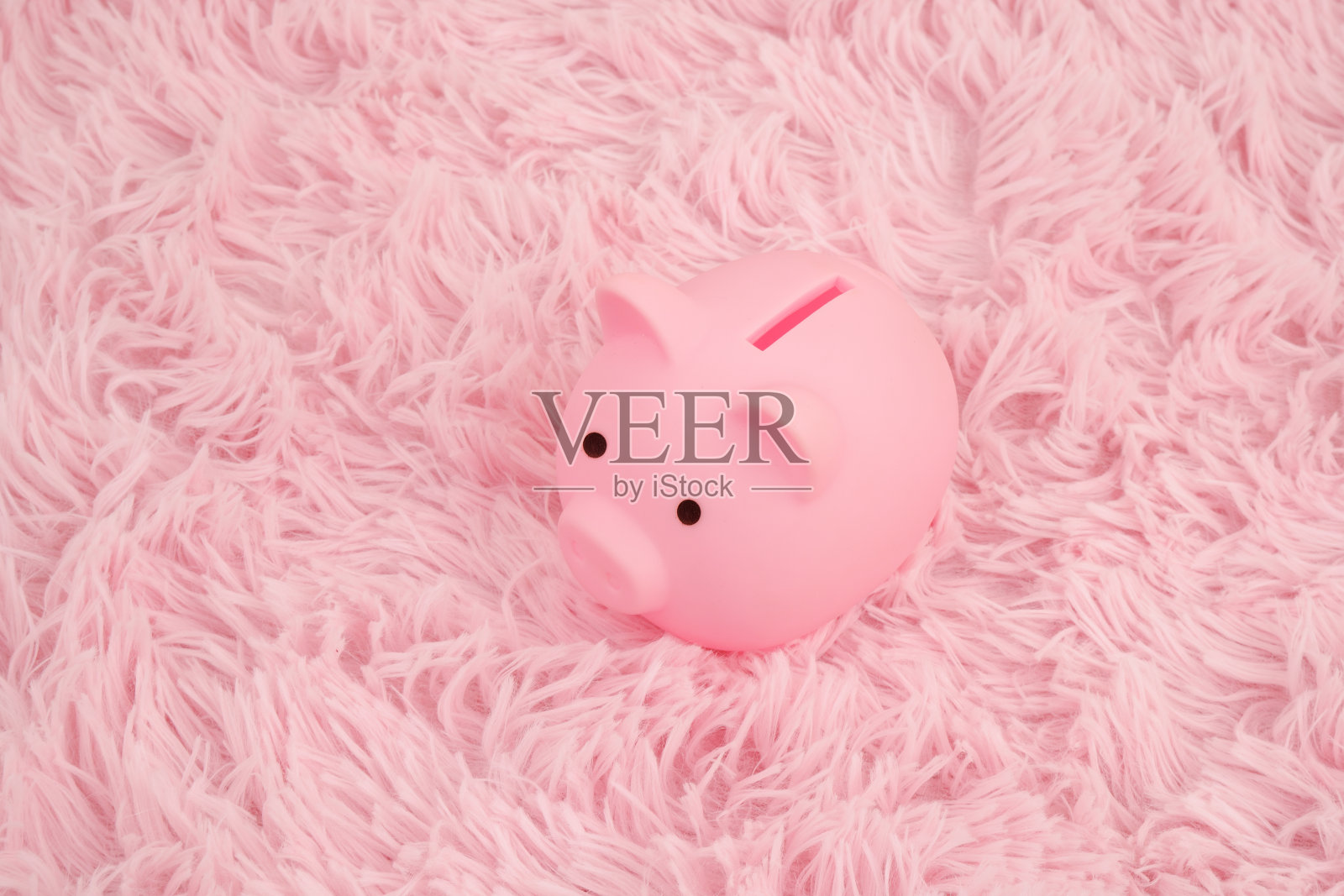 粉色地毯上的粉色储蓄罐。照片摄影图片