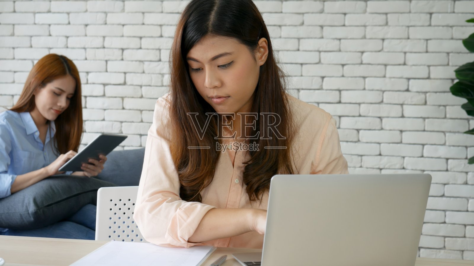 快乐成功的商业女性合作伙伴在公司办公室，公司执行团队合作。与亚洲商务女性高管会面时，用笔记本电脑办公桌举起拳头赢得快乐照片摄影图片