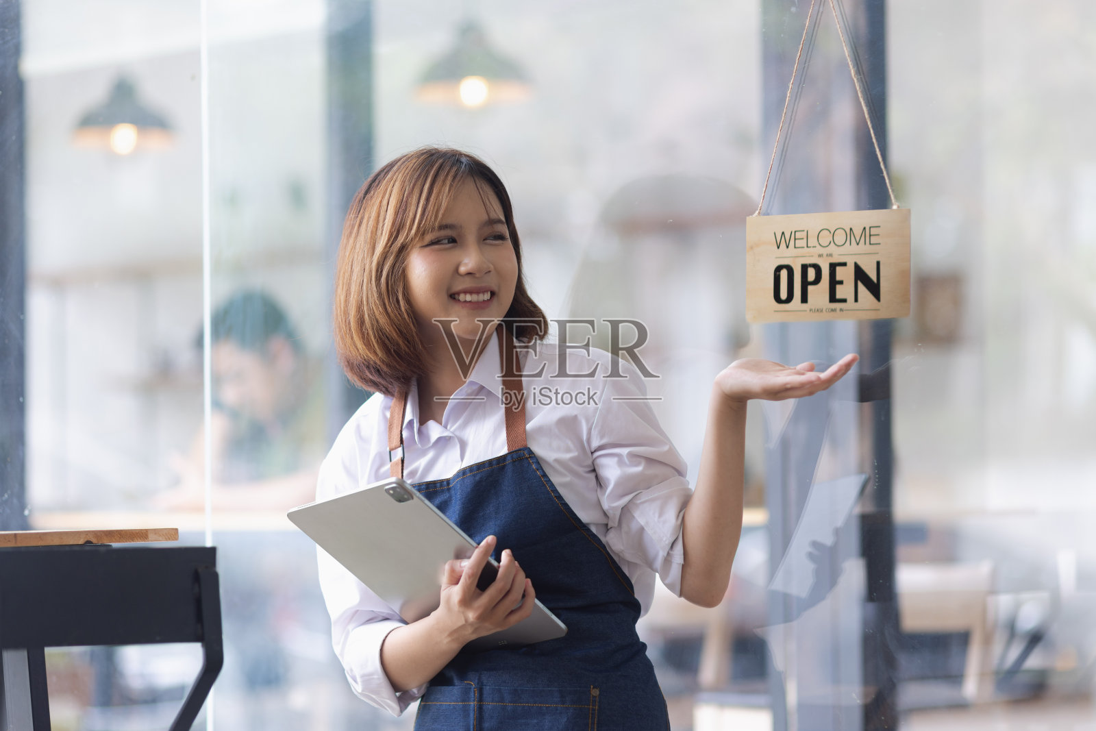 亚洲年轻的女老板在咖啡店里用开着牌子的写字台。照片摄影图片