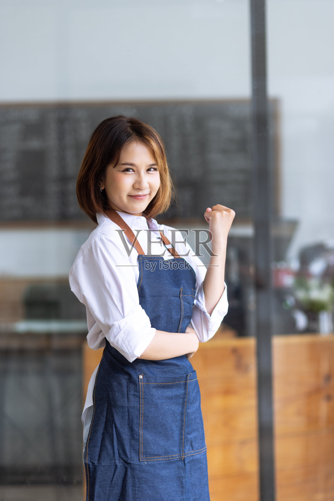 亚洲年轻的老板女孩很高兴成功地在咖啡店里庆祝摊牌开放。照片摄影图片