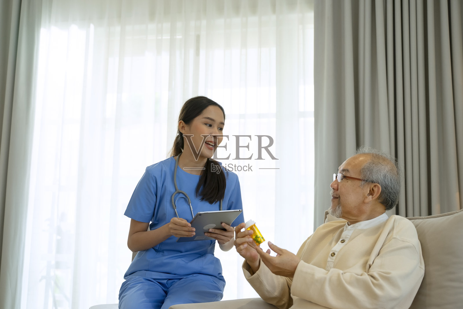 女保健工作者在家照顾老年男子。照片摄影图片