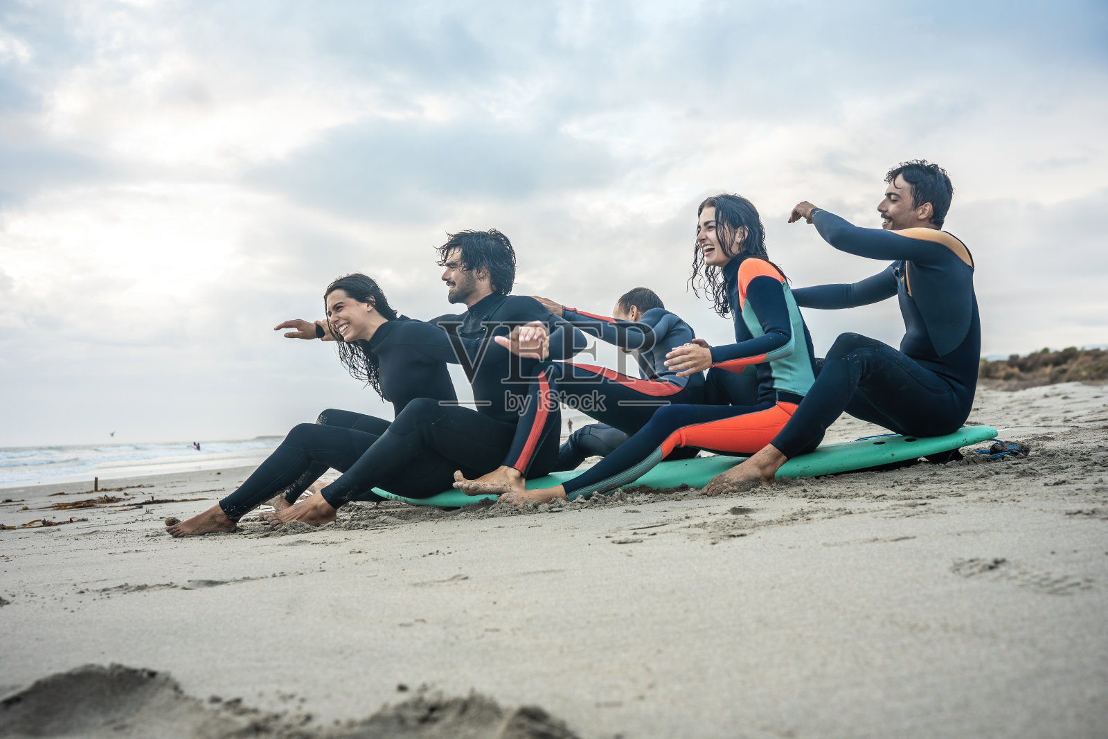朋友们聚集在海边，准备冲浪板，沉浸在海洋充满活力的能量中。照片摄影图片