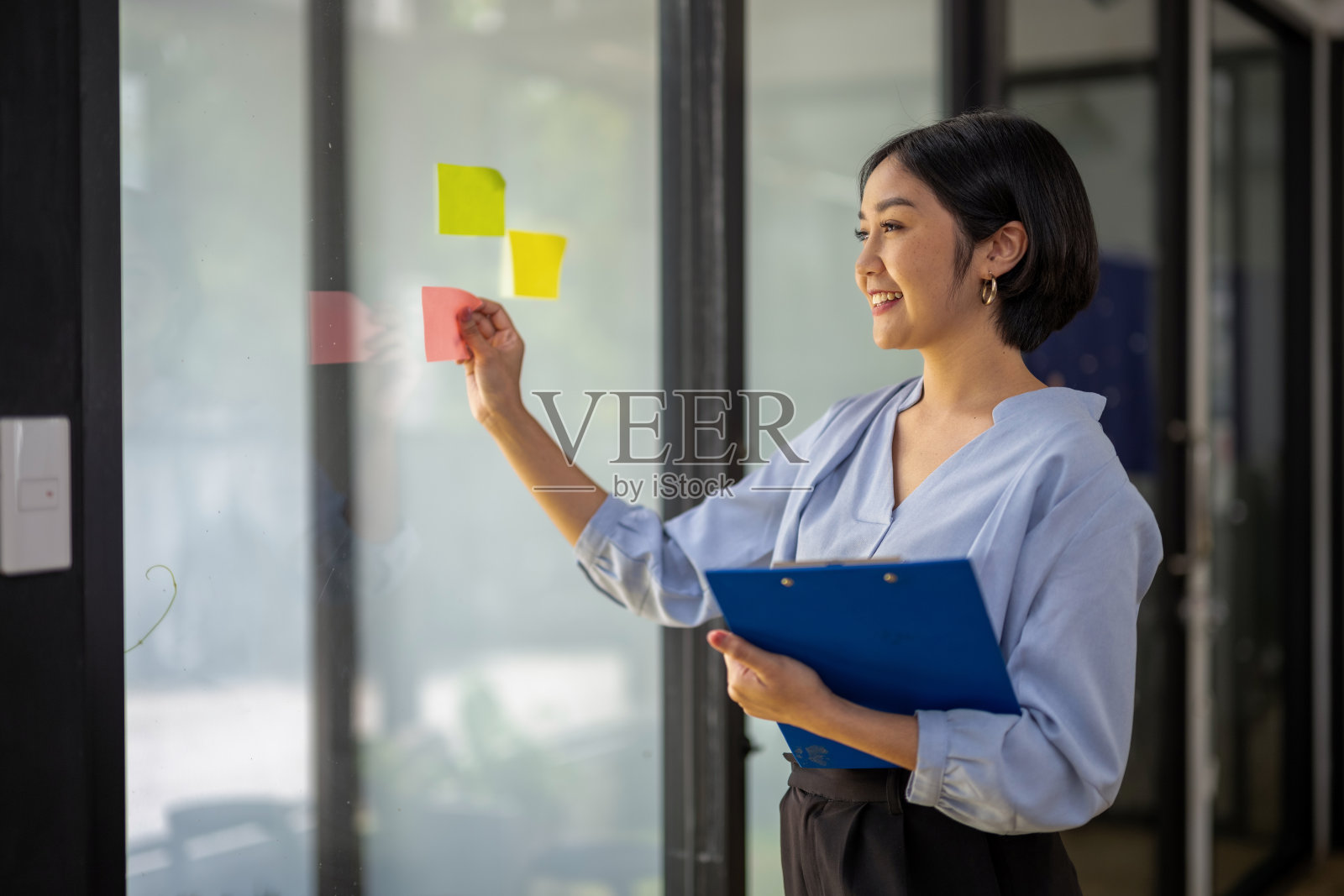 一个女商人把记事本贴在玻璃上，记下新的想法照片摄影图片