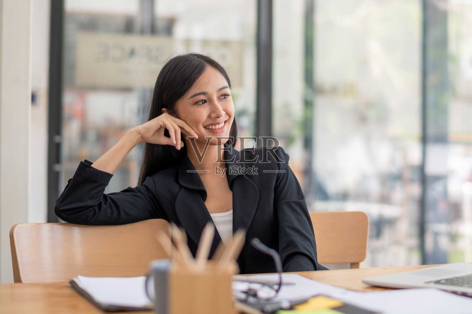 一位女商人坐在办公室里，心情愉快地望着别处照片摄影图片