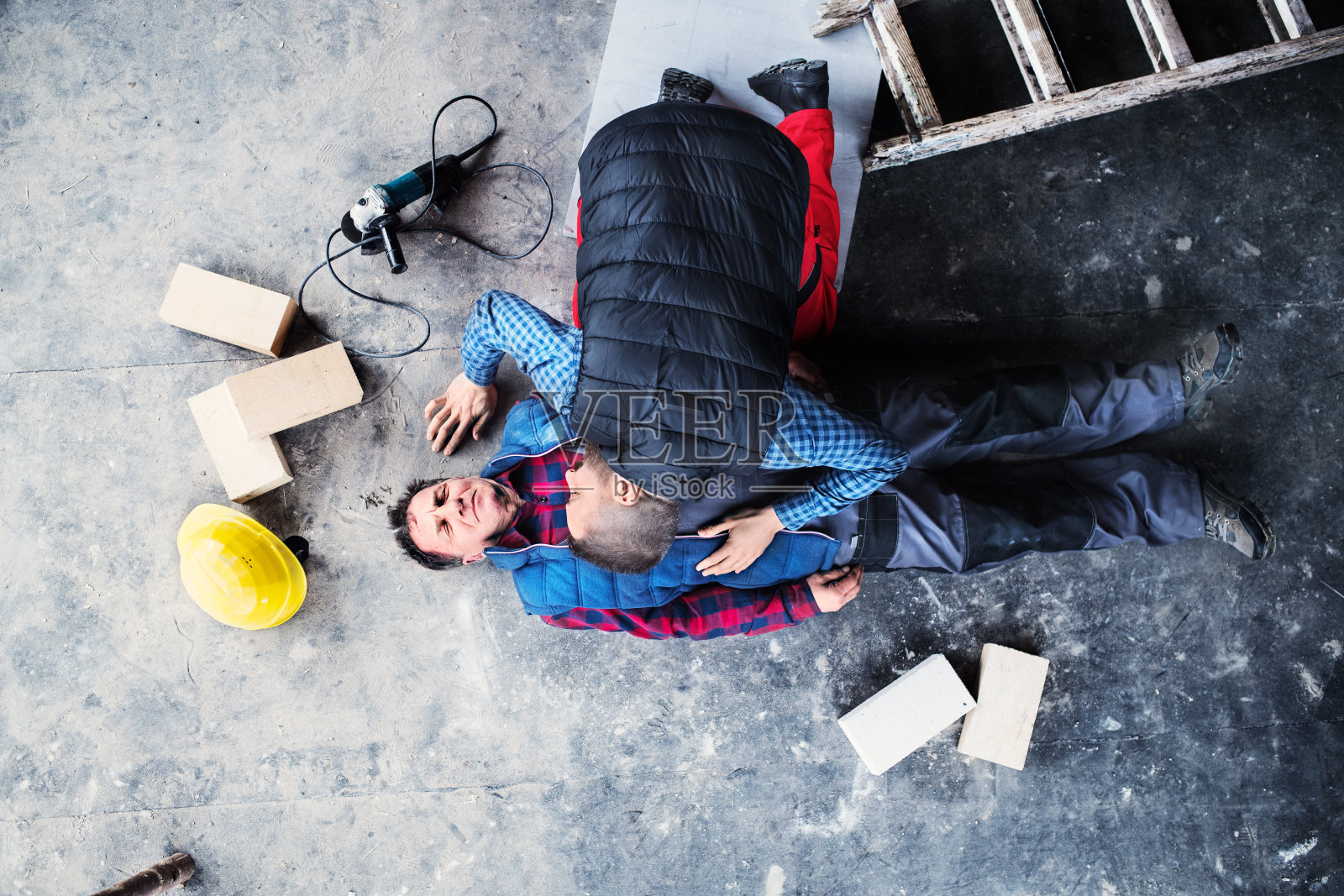 事故后，同事正在为躺在地上的受伤工人进行心肺复苏术。工作场所职业安全和健康的概念。照片摄影图片