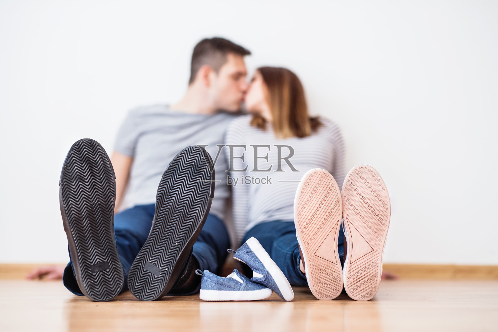 孕妇和她的伴侣，坐在地板上亲吻。照片摄影图片