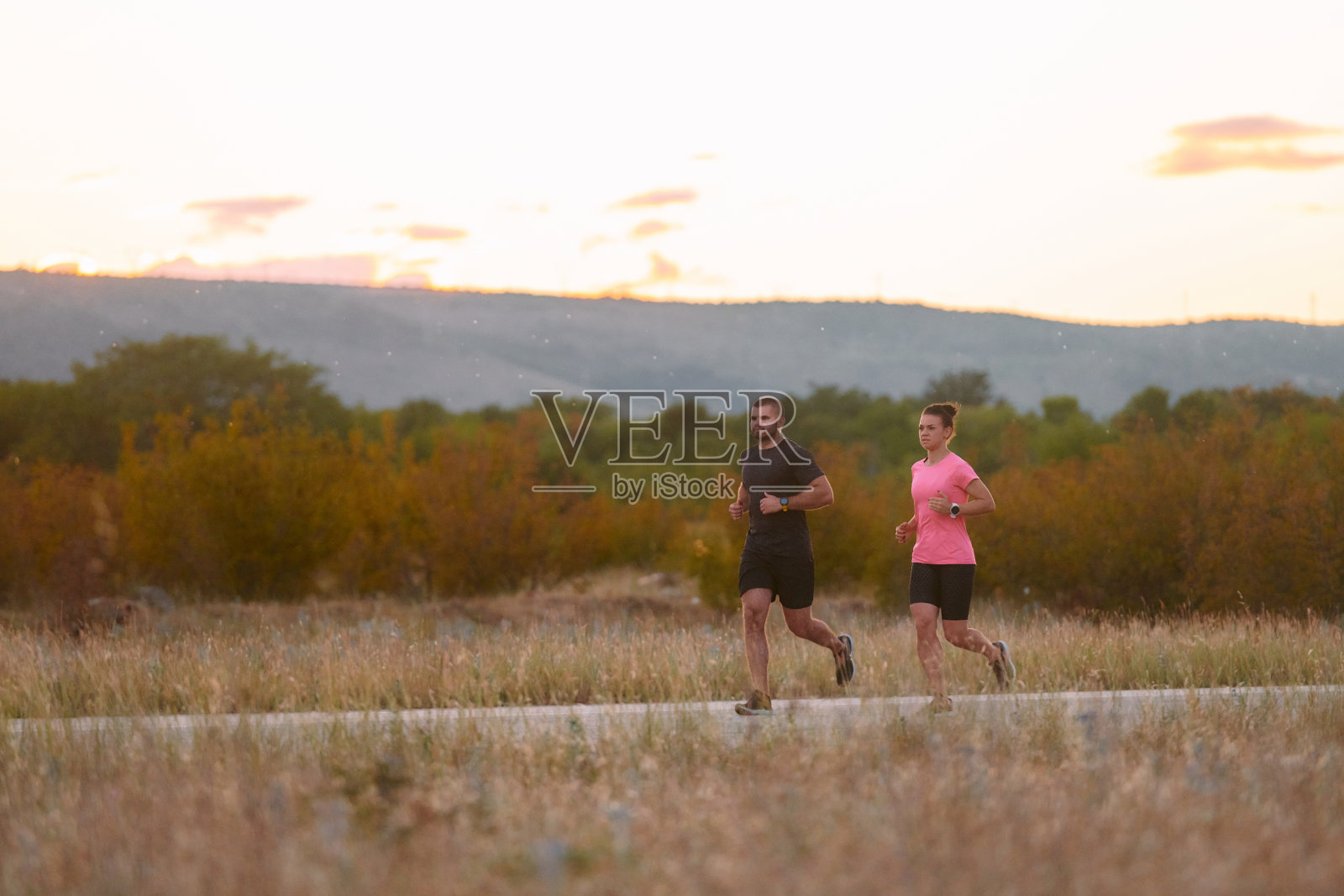 一对穿着运动服的夫妇在一条风景优美的道路上晨练，享受着新鲜的空气，保持着健康的生活方式照片摄影图片