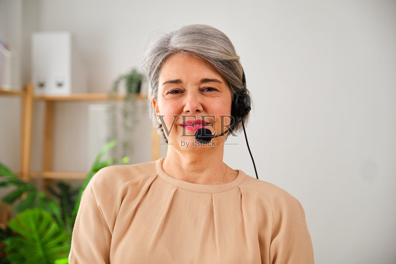 一个成熟的女人在呼叫中心拿着耳机的画像照片摄影图片