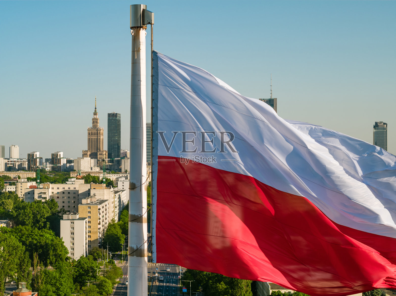 波兰国旗红白相间，映衬着华沙市中心的摩天大楼，蓝天下的空中风景照片摄影图片