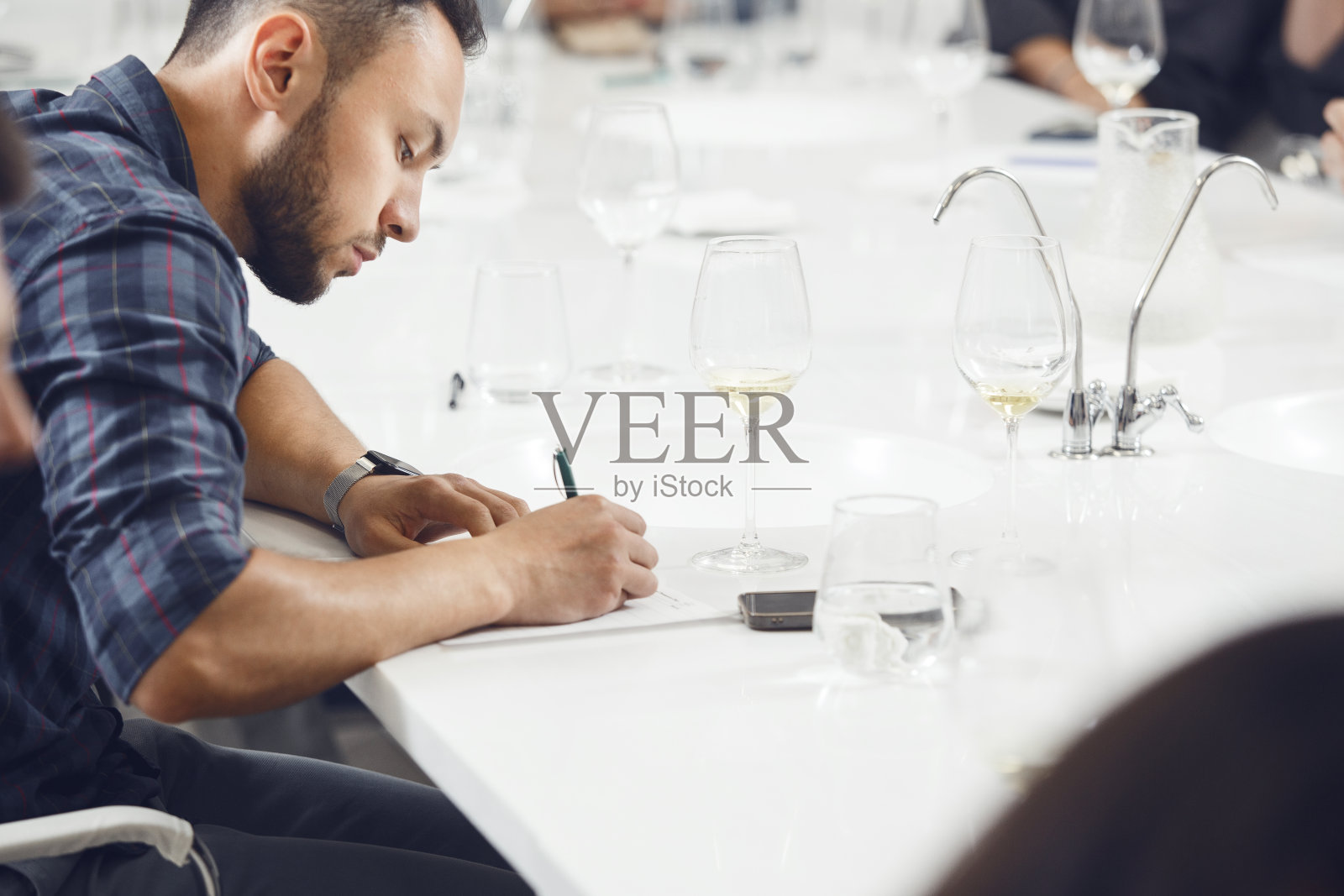 看起来很专业的人在品酒师考试中品酒并在品尝卡上写笔记。葡萄酒酿造师培训。照片摄影图片