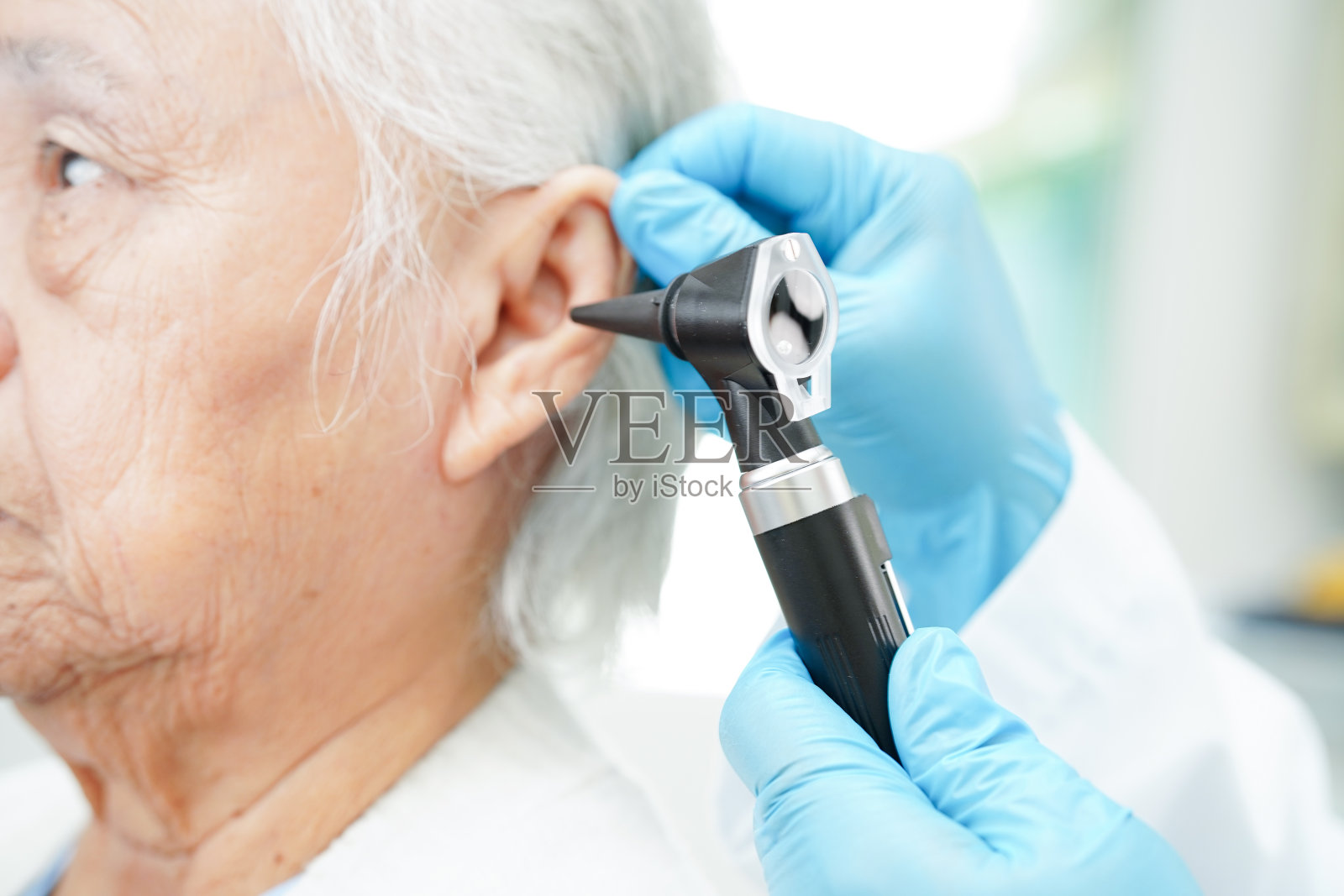 耳鼻喉科医生或耳鼻喉科医生用耳镜检查老年患者的耳朵，听力损失问题。照片摄影图片
