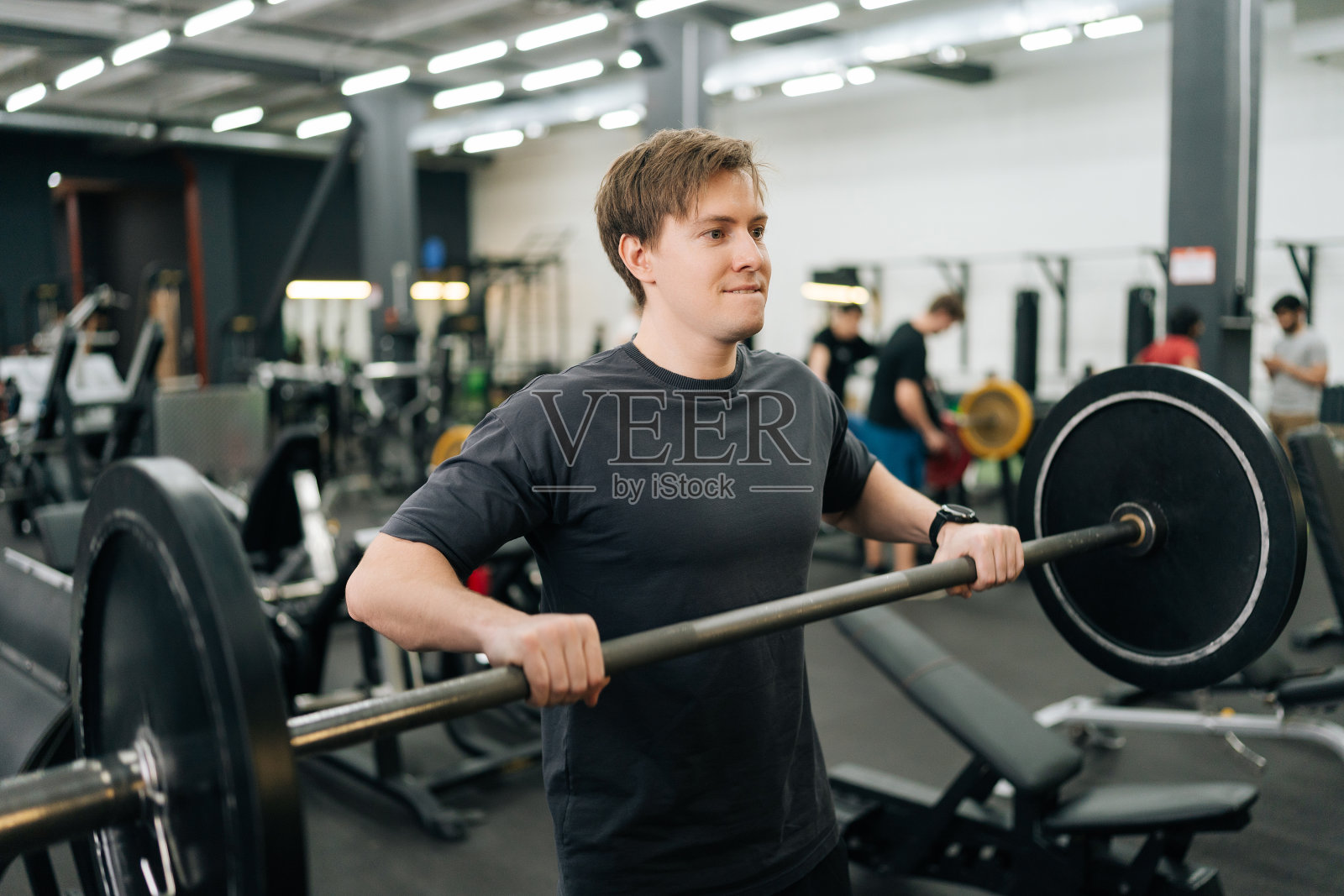 运动员在健身房努力进行杠铃肩部推举照片摄影图片