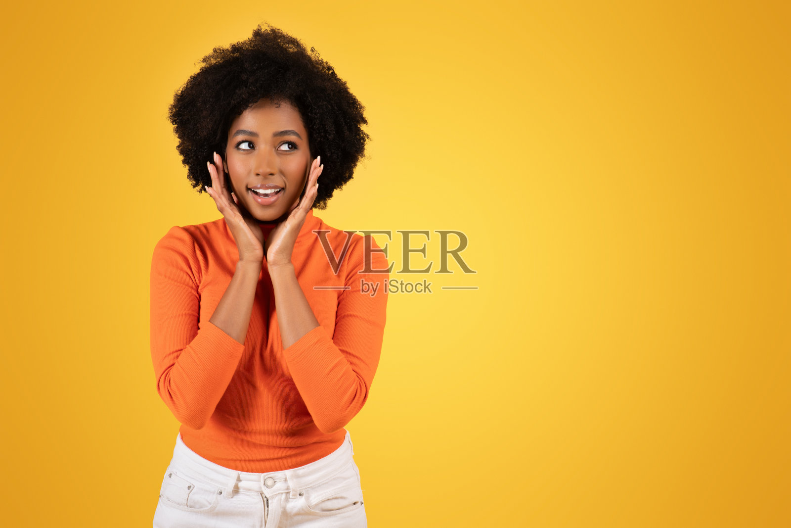 又惊又喜的年轻女子双手放在脸颊上，眼睛睁得大大的照片摄影图片